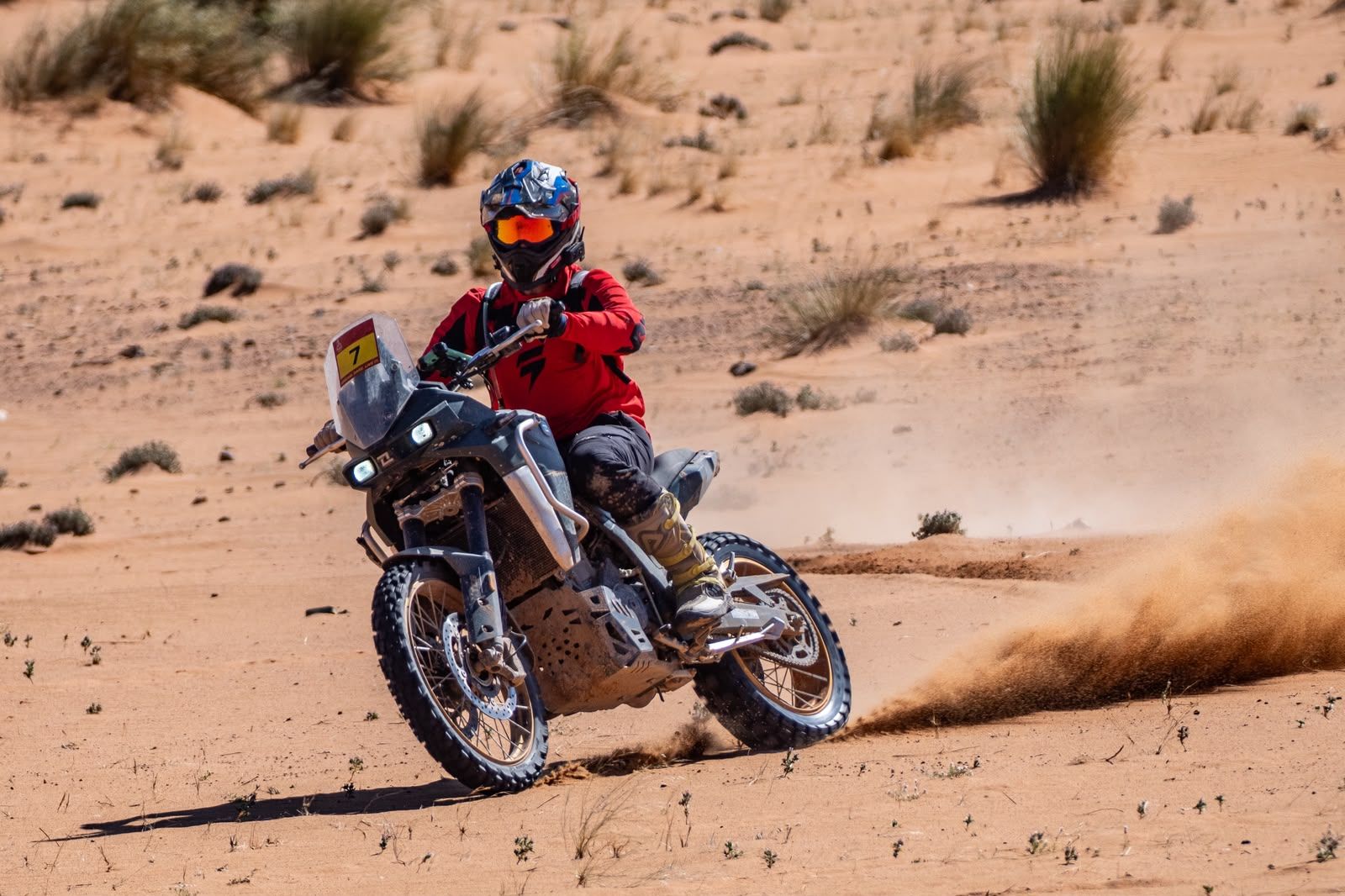 Piloto derrapando en la arena con la moto trail