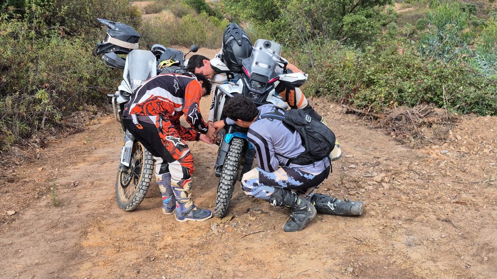 Tres pilotos arreglando una moto en mitad de la pista