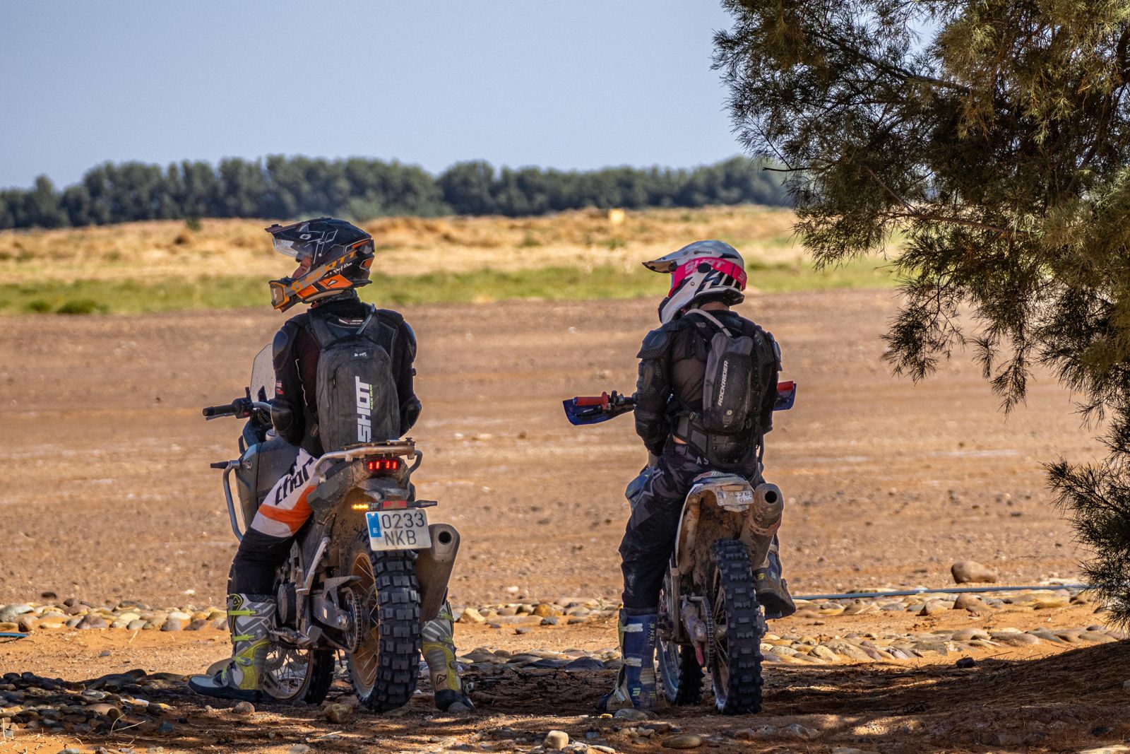Dos pilotos parados a la sombra mirando la pista